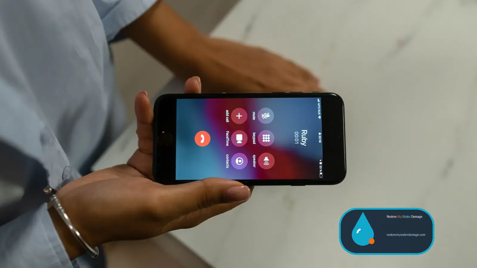 Hand holding a smartphone on a call screen, ready to request water damage help
