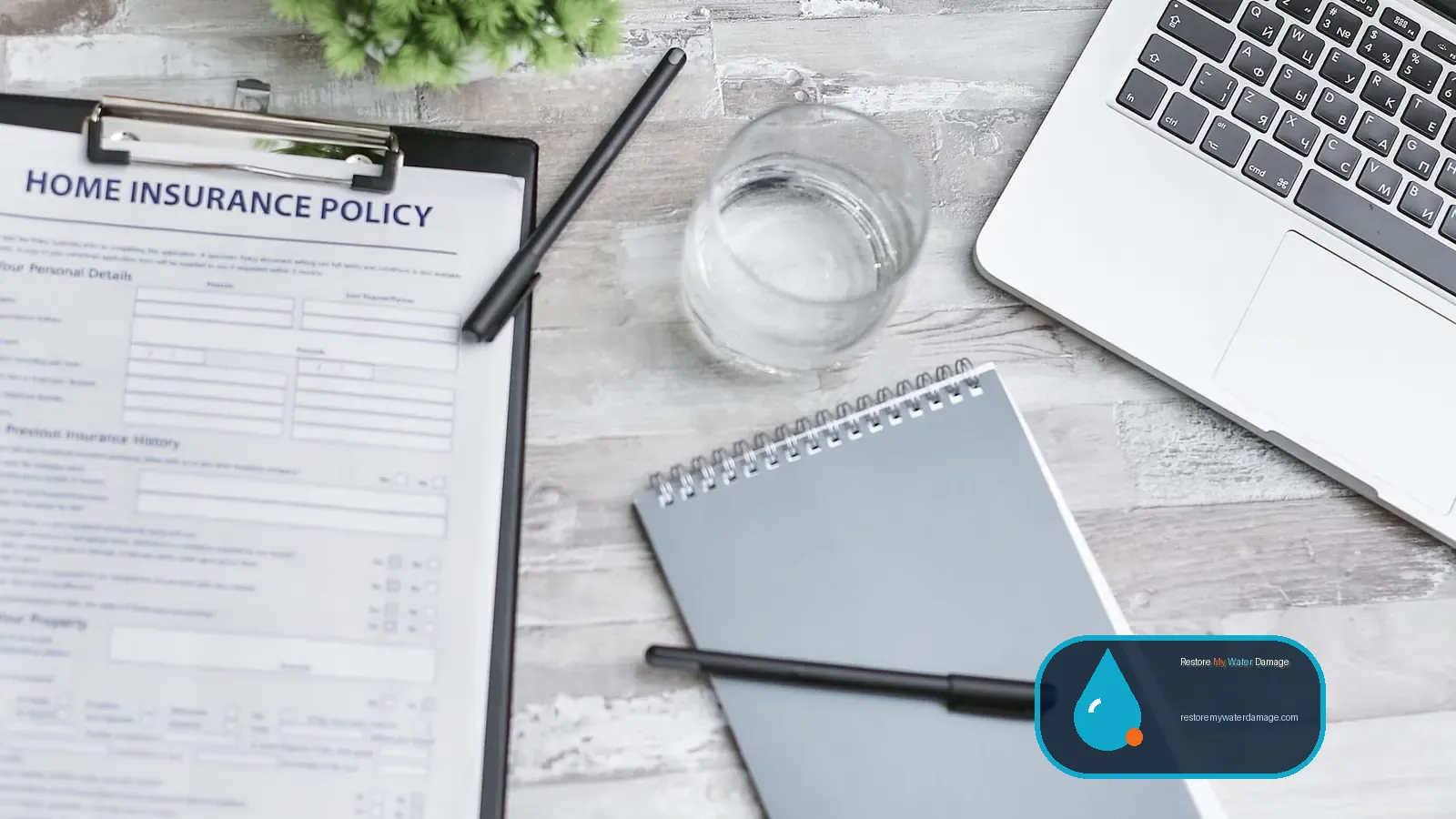 Home insurance policy, notebook and laptop on a table while checking sewage backup cleanup coverage