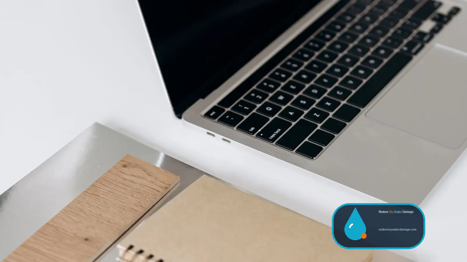 Open laptop and notebooks on a tidy white desk for browsing water damage resources