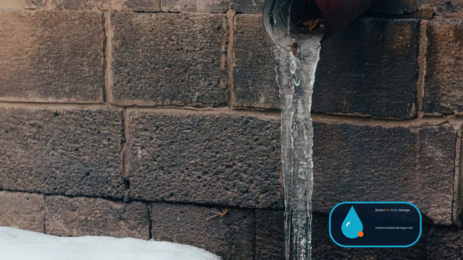 Frozen pipe dripping ice against a stone wall in winter, needing water damage restoration in Berks County Reading