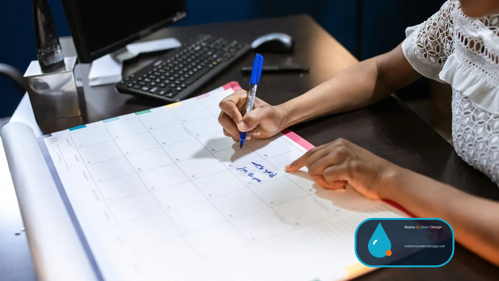 Hand writing on a desk calendar to schedule each step of the water damage restoration process